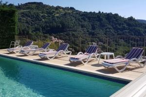 a row of lounge chairs next to a swimming pool at Gîte Olivier in Vals-les-Bains