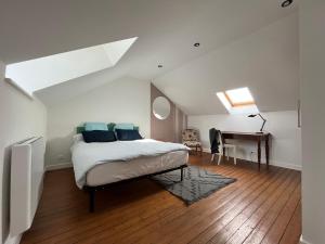 ein Schlafzimmer mit einem Bett und einem Schreibtisch im Dachgeschoss in der Unterkunft Sur les toits de Fontainebleau - Hypercentre in Fontainebleau