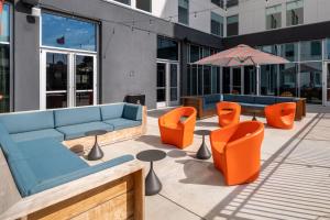 a patio with couches and orange chairs and an umbrella at Aloft Austin South in Austin