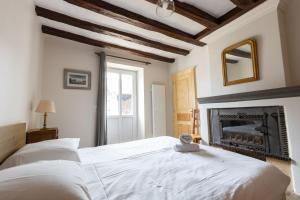 a bedroom with a white bed and a fireplace at Le Pressoir in Meusnes