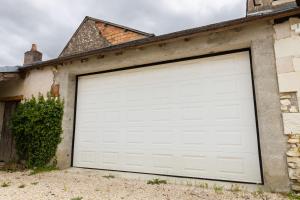 a white garage door on the side of a house at Le Pressoir in Meusnes