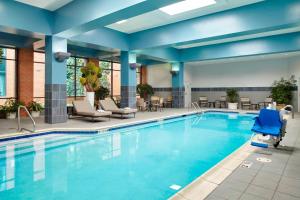 una piscina en el vestíbulo del hotel con sillas y mesas en Marriott Cincinnati Airport en Hebron