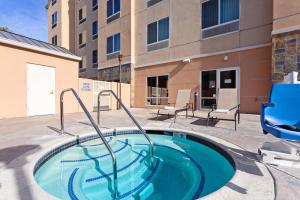 una piscina con 2 sillas y un edificio en Fairfield Inn & Suites - Los Angeles West Covina, en West Covina