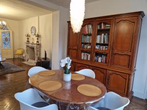 uma sala de jantar com uma mesa de madeira e cadeiras brancas em Gîte de charme dans une maison bourgeoise em Frameries