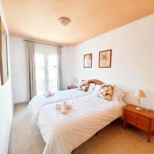 Apartamentos Vicenta Playa Carihuela في توريمولينوس: سريرين في غرفة بيضاء مع نافذة