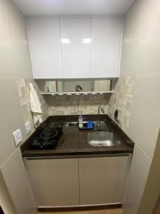a small kitchen with a sink and white cabinets at Encantador Apto na Beira do Lago! in Brasilia