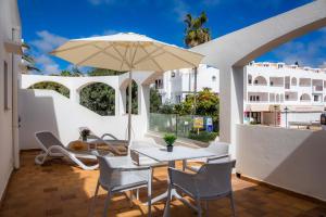 une terrasse avec une table, des chaises et un parasol dans l'établissement White suites 2, à Cala d´Or