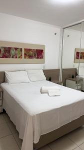 a large white bed with two towels on it at Refúgio Beira Lago- Life Resort in Brasilia