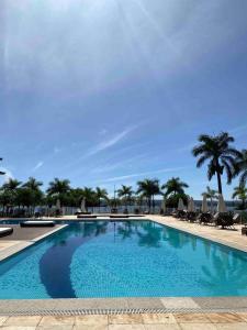 a large swimming pool with chairs and palm trees at Refúgio Beira Lago- Life Resort in Brasilia