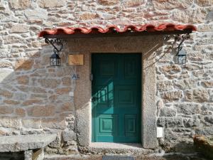 una puerta verde en un edificio de piedra con techo rojo en Casa de Maçaneira en Miranda do Douro