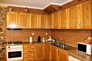 a kitchen with wooden cabinets and a sink at Casa de Maçaneira in Miranda do Douro