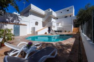 uma casa branca com piscina e cadeiras em White suites 3 em Cala d´Or