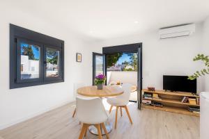 een woonkamer met een tafel en stoelen en een televisie bij White suites 3 in Cala d´Or