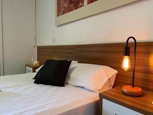 - une chambre avec un lit blanc et une tête de lit en bois dans l'établissement Harmonia à Beira do Lago - Life Resort, à Brasilia