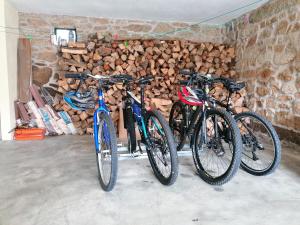 tre biciclette parcheggiate accanto a un mucchio di legno di Casa de Maçaneira a Miranda do Douro