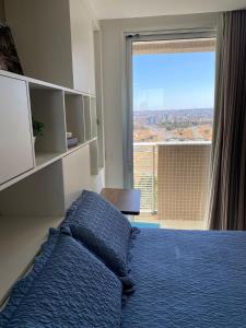 a bedroom with a blue bed and a large window at Incrível Apto DF Plaza com vista in Brasilia