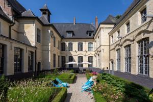 a courtyard of a castle with two blue chairs at L'Hermitage Gantois, Autograph Collection in Lille