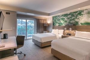 a hotel room with two beds and a desk at Courtyard by Marriott Jekyll Island in Jekyll Island