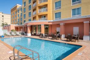 a swimming pool with tables and chairs next to a building at Courtyard Jacksonville Orange Park in Orange Park