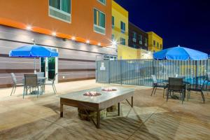 eine Terrasse mit Tischen, Stühlen und blauen Sonnenschirmen in der Unterkunft Fairfield Inn & Suites by Marriott Bakersfield North/Airport in Bakersfield