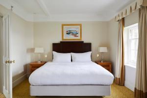 a bedroom with a large white bed with two lamps at Bournemouth Highcliff Marriott Hotel in Bournemouth