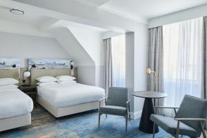 a hotel room with two beds and a table and chairs at Bournemouth Highcliff Marriott Hotel in Bournemouth