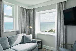 a living room with a couch and a large window at Bournemouth Highcliff Marriott Hotel in Bournemouth
