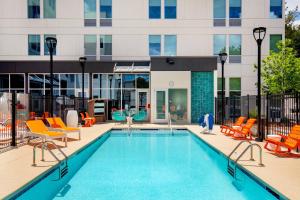 a swimming pool with orange chairs and a building at Aloft Dallas DFW Airport Grapevine in Coppell