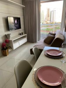 a living room with a dining table and a television at Excelente Ap no DF Century Plaza in Brasilia