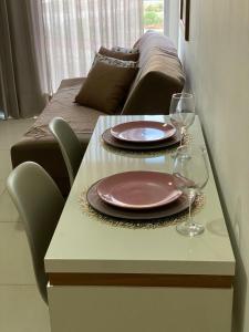 a table with two plates and wine glasses on it at Excelente Ap no DF Century Plaza in Brasilia