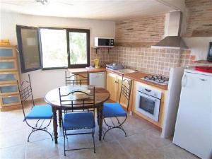 Una cocina con mesa y sillas y un refrigerador. en CAROLE F2, en Sainte-Lucie de Porto-Vecchio