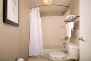 a bathroom with a white shower curtain and a toilet at Springhill Suites by Marriott Jacksonville Airport in Jacksonville