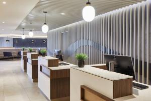 a lobby with a row of reception desks with plants at Courtyard by Marriott London Heathrow Airport in Hayes