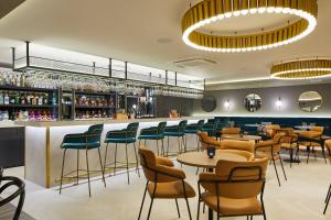 a restaurant with tables and chairs and a bar at Courtyard by Marriott London Heathrow Airport in Hayes