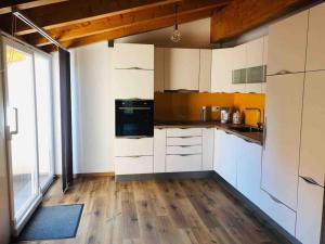 a kitchen with white cabinets and a large window at Mansarda / Loft open space in Signora