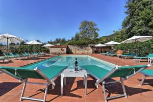 a pool with chairs and a table and a bottle of wine at Agriturismo Villa Rosselmini in Calci