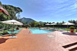 カルチにあるAgriturismo Villa Rosselminiのパラソルとラウンジチェア付きのスイミングプールを利用できます。