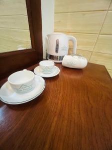 a wooden table with two plates and a coffee maker at XUÂN HUỲNH 3 Hotel in Soc Trang