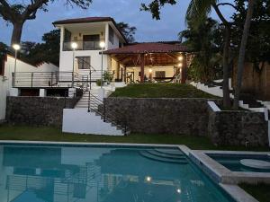 a house with a swimming pool in front of a house at Habitaciones Casa Cuscatlan in Tamanique
