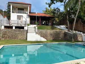 a house with a swimming pool in front of a house at Habitaciones Casa Cuscatlan in Tamanique