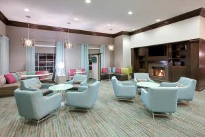a waiting room with chairs and tables and a fireplace at Residence Inn Midland in Midland