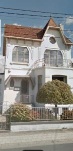 Una casa blanca con un árbol delante. en Gîte de charme dans une maison bourgeoise en Frameries