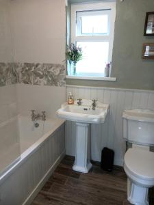 a bathroom with a sink and a toilet and a window at Peggys Escape in Ballycastle