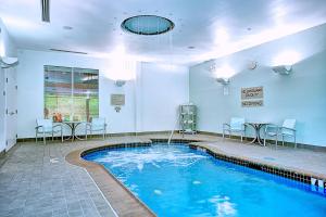 a swimming pool with chairs and a table in a room at SpringHill Suites Harrisburg Hershey in Harrisburg