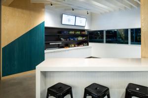 a kitchen with a white counter and stools at Aloft North Kansas City in Kansas City