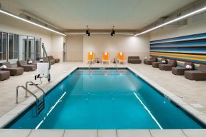uma piscina num quarto com cadeiras e mesas em Aloft North Kansas City em Kansas City
