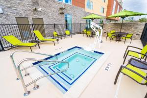 - une piscine sur une terrasse avec des chaises et des tables dans l'établissement SpringHill Suites by Marriott Ontario Airport/Rancho Cucamonga, à Ontario