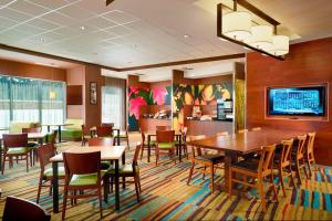 Fairfield Inn & Suites by Marriott Hendersonville Flat Rock في فلات روك: غرفة طعام مع طاولات وكراسي وتلفزيون