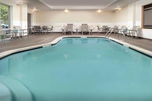 una piscina en una habitación de hotel con sillas y mesas en Fairfield Inn & Suites Baltimore BWI Airport, en Linthicum