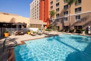 a large swimming pool in a courtyard with buildings at Courtyard by Marriott Baldwin Park in Baldwin Park